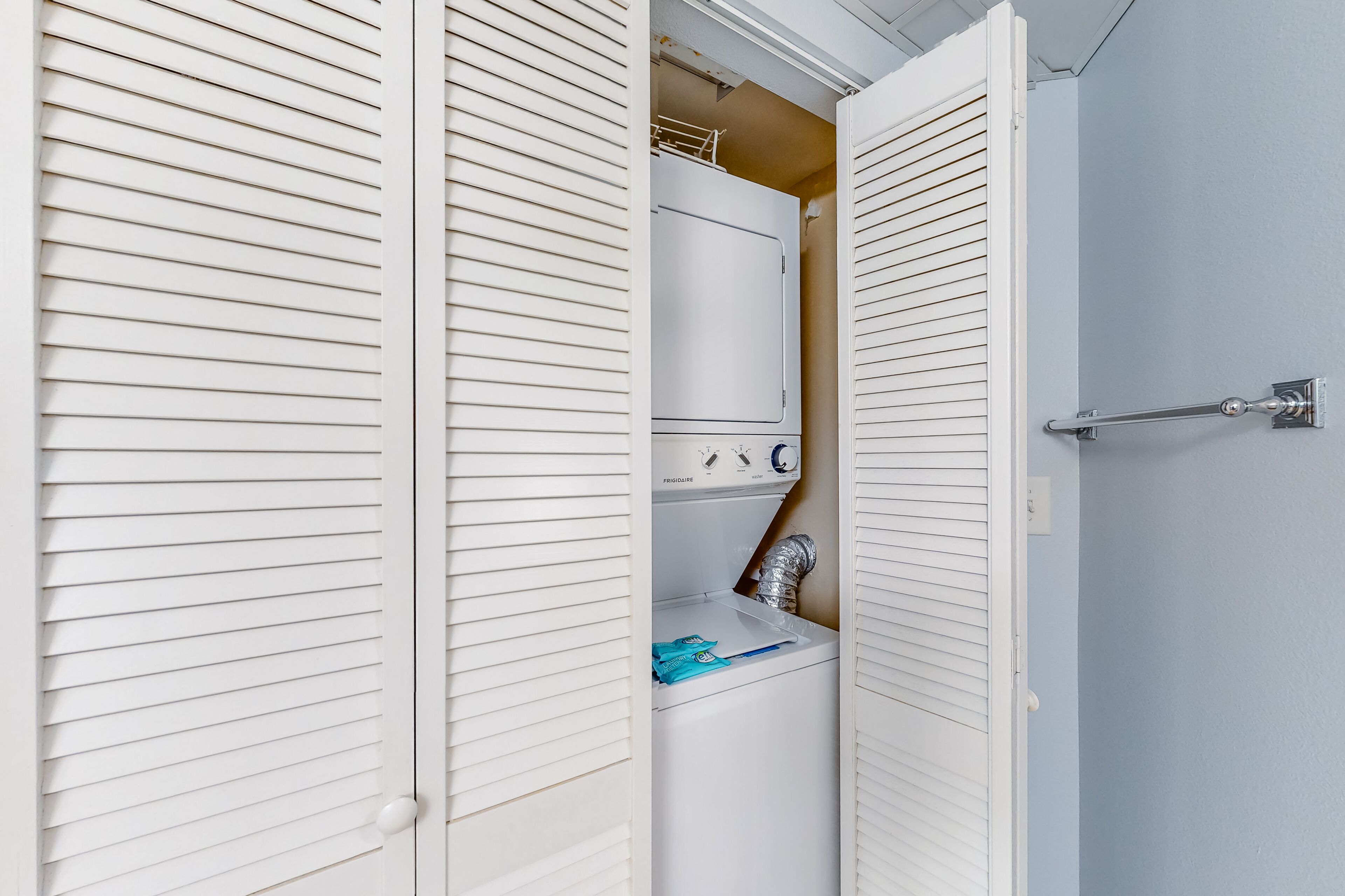 A laundry room with a white washing machine, a dryer, and a metal rack.