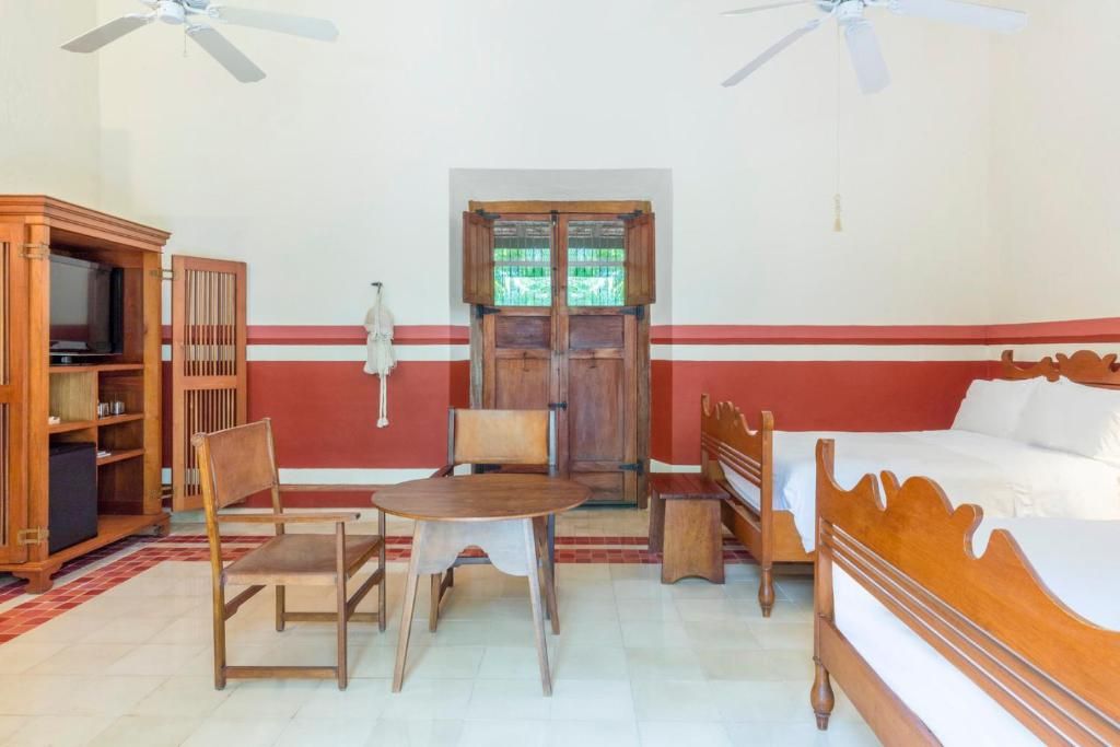 A room with a bed, a wooden table, two chairs, a television, and a wardrobe.