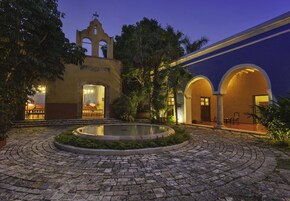 Un patio con una fuente, una iglesia y un edificio con arcos.