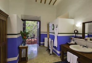 A bathroom with a large sink, mirror, and towel rack. There is a door leading to an outdoor area with a table and chairs.