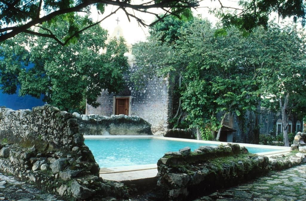 Une cour avec une piscine, des murs en pierre et une végétation luxuriante.