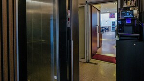 An elevator, a coffee station, and a glimpse of a dining area. - Hotel Münchner Hof (Frankfurt)