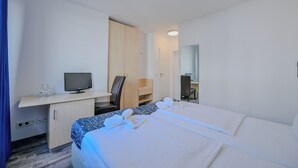 A hotel room with a bed, a desk with a computer, a television, and a mirror. - Hotel Münchner Hof (Frankfurt)