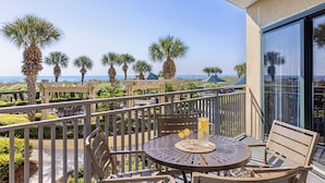 A balcony with a round table and chairs, a drink with lemons, and palm trees in the background. - Marriott's Barony Beach Club (Hilton Head Island)