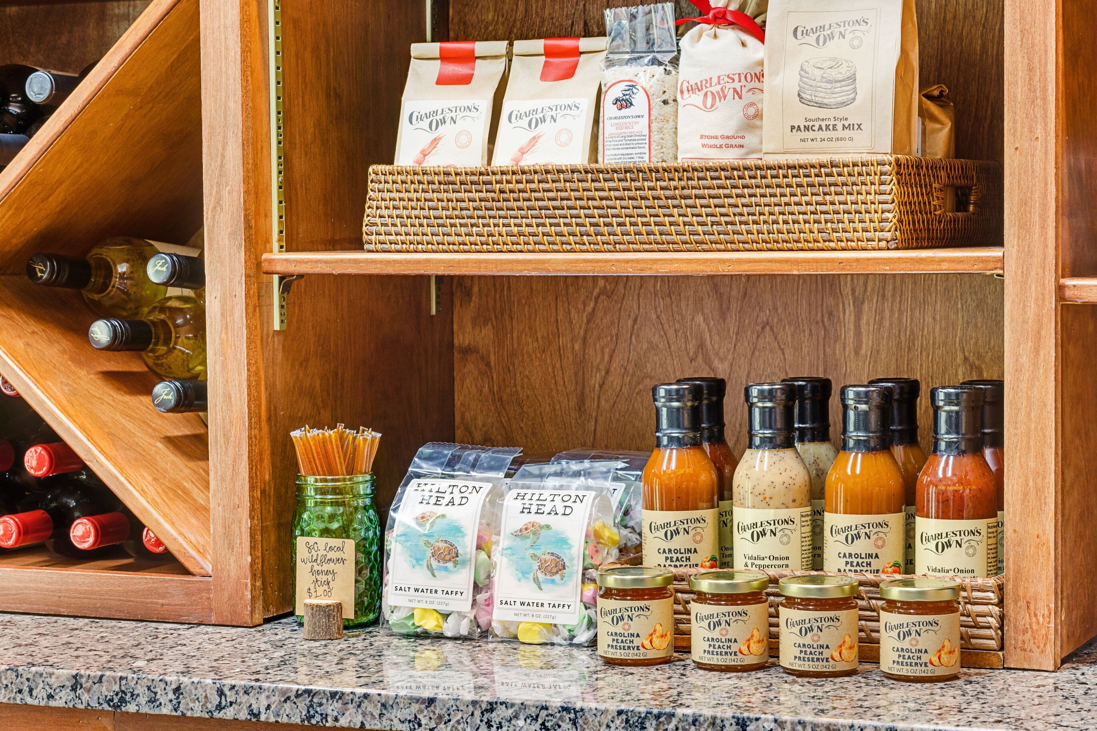Une cuisine avec des étagères en bois où sont rangés divers produits alimentaires, notamment des pots de confitures et des bouteilles de sauces.