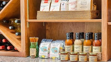 A kitchen with wooden shelves holding various food items, including jars of preserves and bottles of sauces.