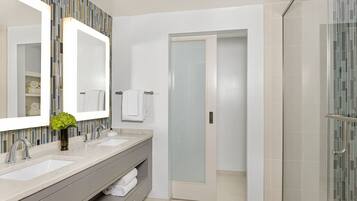 Un baño moderno con dos lavamanos, un espejo grande y una zona de ducha.