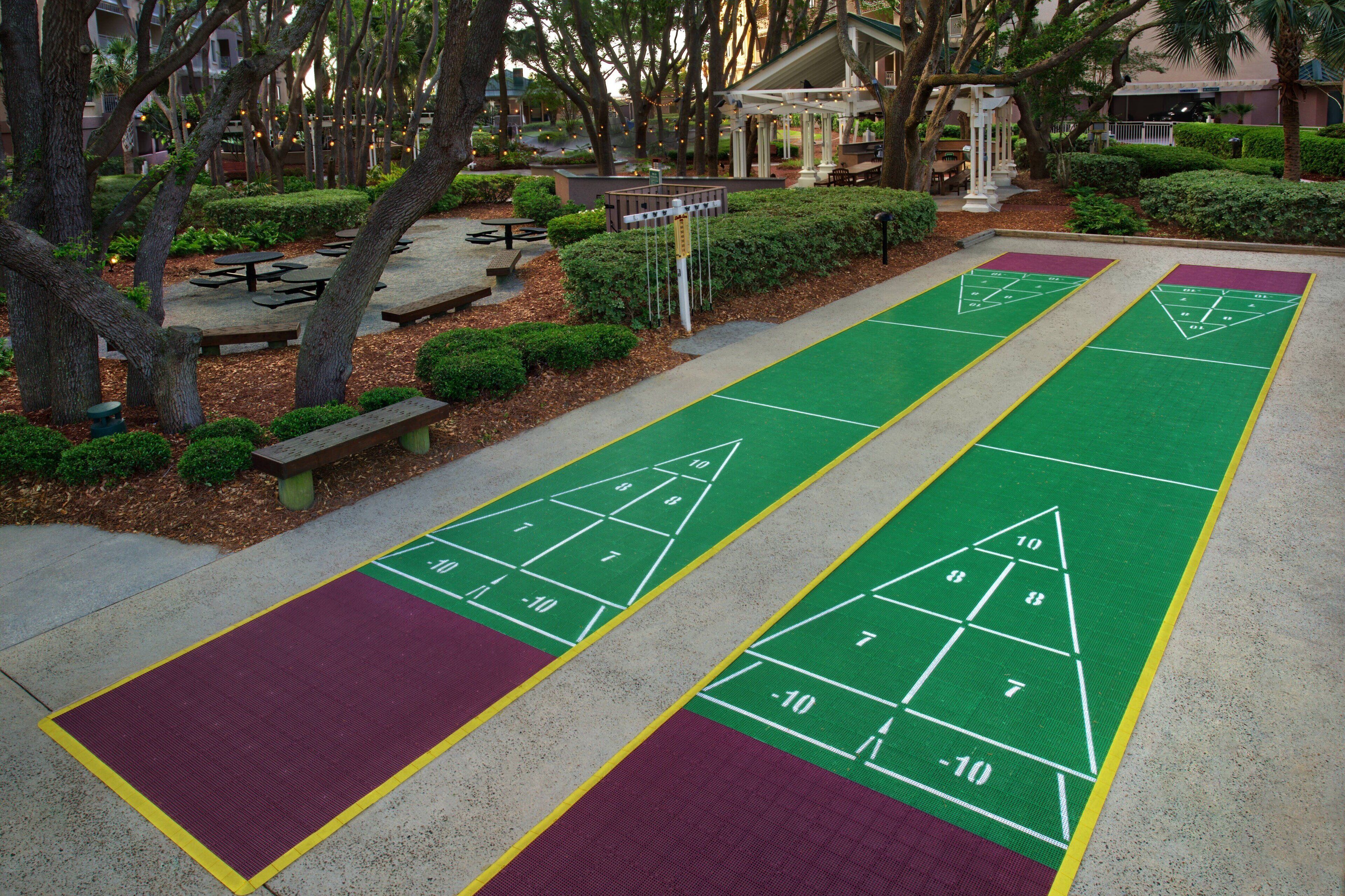 A courtyard with shuffleboard courts, benches, and a gazebo.
