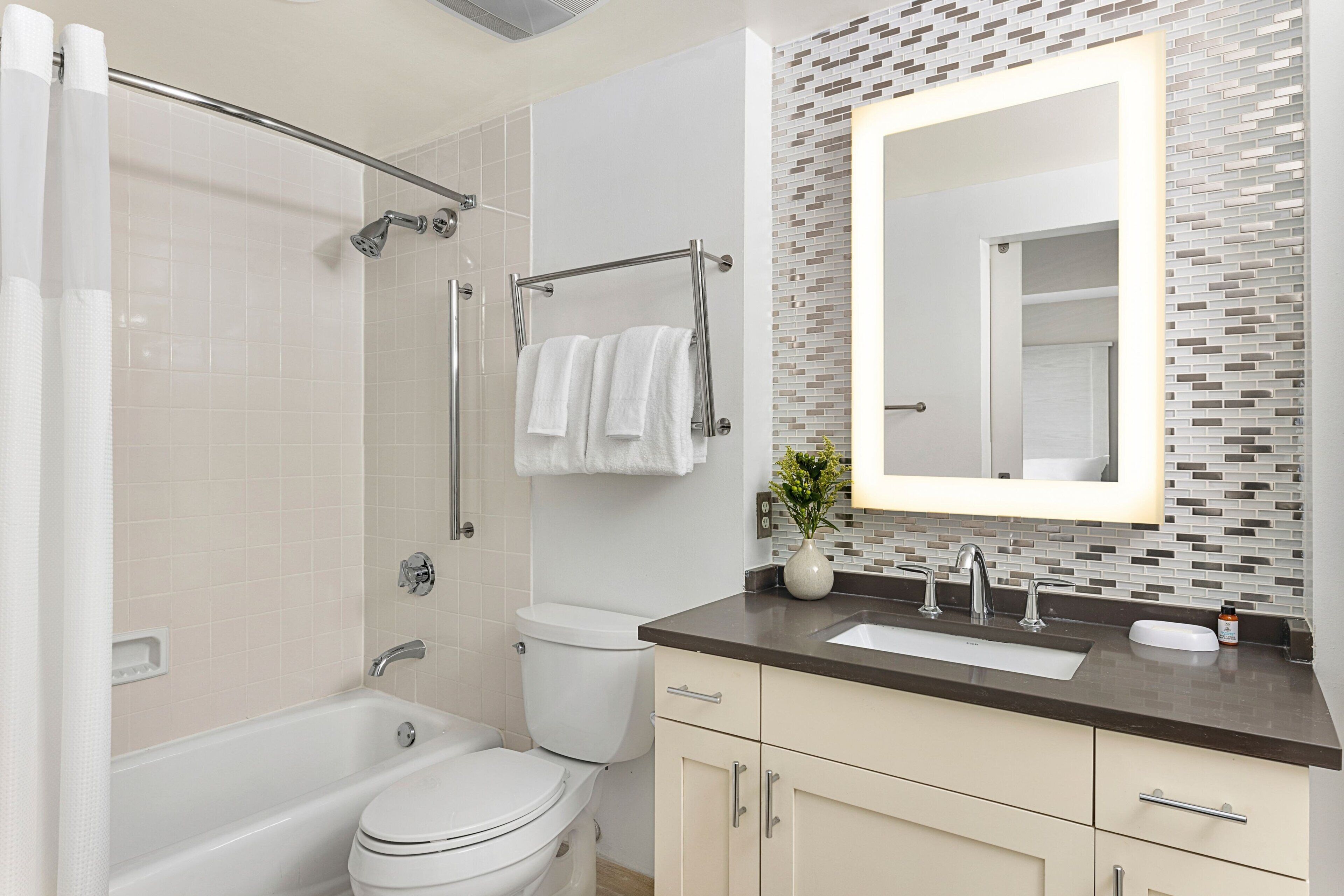 Une salle de bain moderne équipée d’une baignoire, de toilettes et d’un meuble-lavabo avec un miroir.