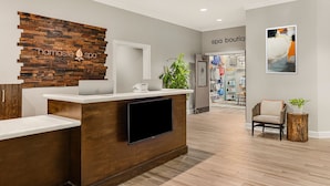A reception area with a wooden reception desk, a flat-screen TV, and a wall-mounted sign that reads "namaste spa". - Marriott's Barony Beach Club (Hilton Head Island)