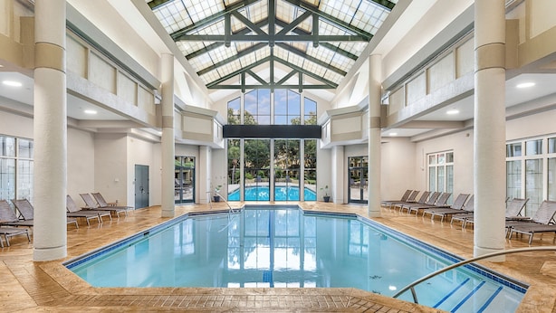An indoor swimming pool with clear glass ceilings, multiple lounge chairs, and a view of the outdoors. - Marriott's Barony Beach Club (Hilton Head Island)