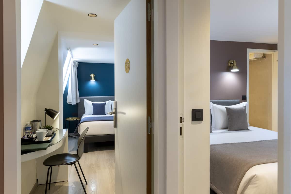 Une chambre d’hôtel équipée d’un bureau, d’une chaise et de deux lits.
