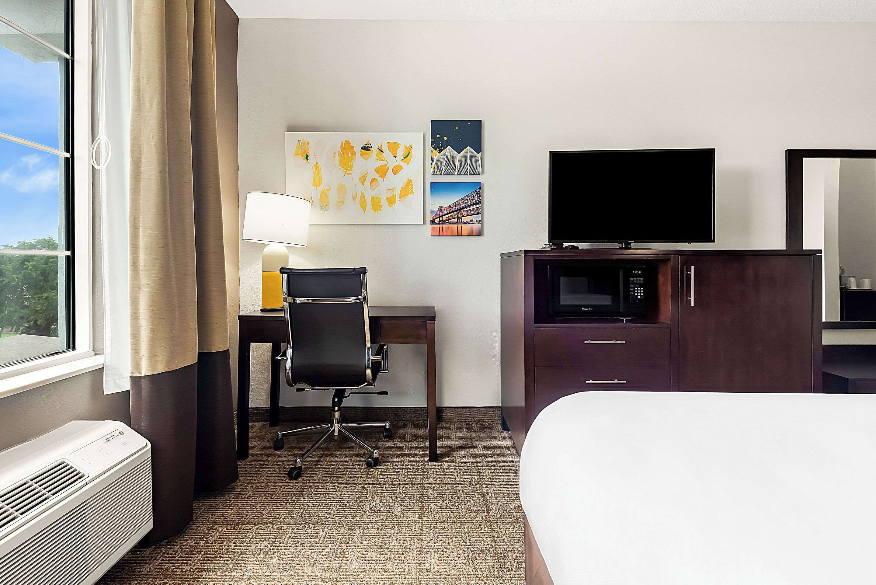 Habitación de hotel con cama, escritorio, silla, televisor y microondas.