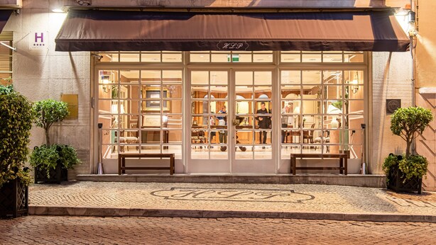 A boutique hotel entrance with a large glass facade, a covered entrance, and a cobblestone pavement. - Hotel Lisboa Plaza, a Lisbon Heritage Collection (Lisbon)