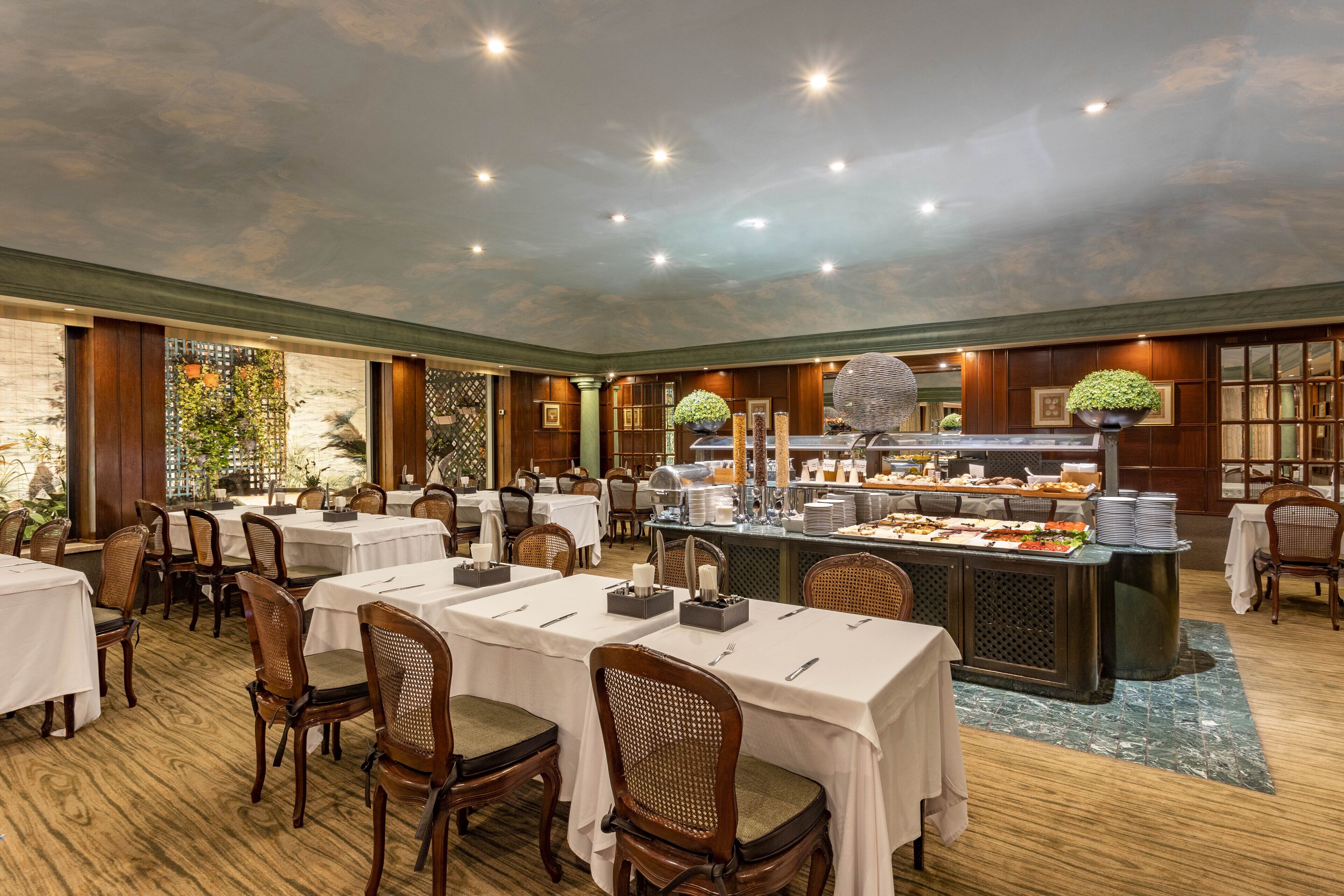 A restaurant with round tables, chairs, and a buffet area.