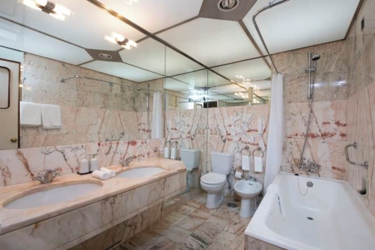 Une salle de bain moderne avec des murs en marbre, une grande baignoire et un meuble-lavabo à deux vasques.