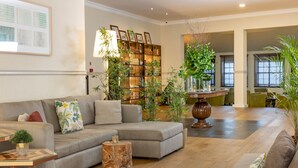 A spacious living area with a grey sofa, wooden coffee table, and a bookshelf filled with books and decorative items. - Hotel Lisboa Plaza, a Lisbon Heritage Collection (Lisbon)