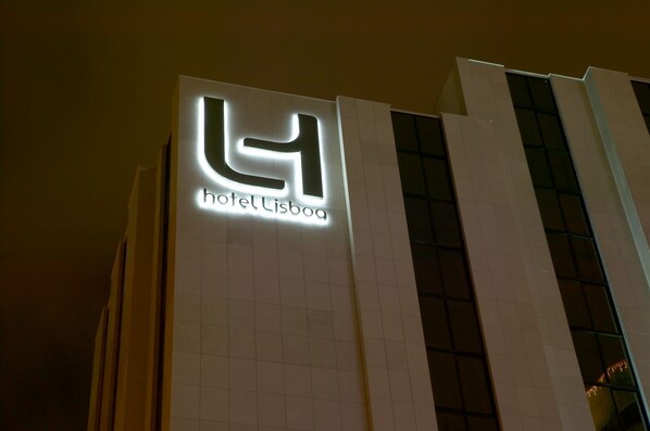 Un edificio moderno con un logotipo iluminado y el nombre "hotel Lisboa" en su fachada.