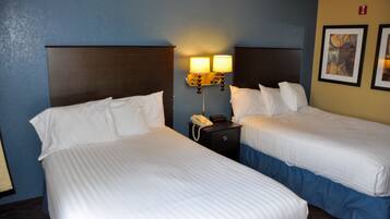 Une chambre d’hôtel avec deux lits simples, une table de chevet avec un téléphone et une lampe fixée au mur.