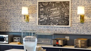 Una cocina con decoración mural de pizarra, dos luces empotradas, un microondas, un tostador y un dispensador de agua.