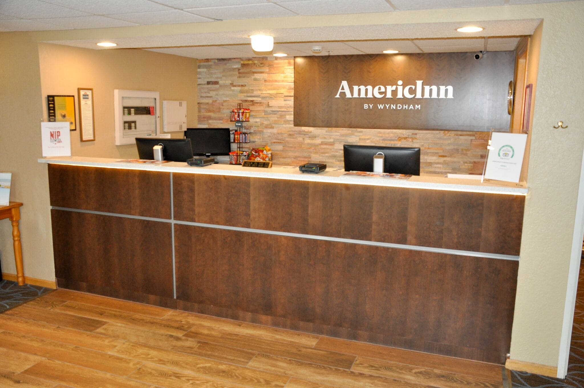 Un comptoir d’accueil en bois, un téléviseur à écran plat et un petit réfrigérateur sont à la disposition des clients à l’hôtel AmericInn by Wyndham.