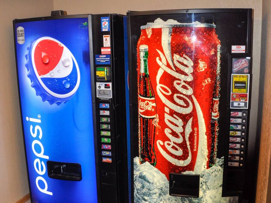 Dues màquines expenedores, una de Pepsi i una de Coca-Cola, en una habitació amb un paviment decorat.