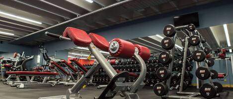 Un gimnasio con varios equipos de ejercicio, incluyendo mancuernas y máquinas de pesas.