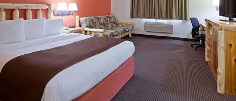 Habitación de hotel con una cama grande, un sofá, un escritorio con televisor y un equipo de aire acondicionado.