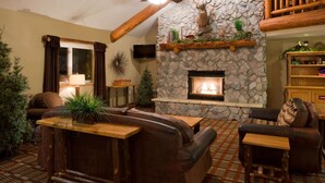 A cozy living room with a stone fireplace, leather sofas, and a wooden coffee table.