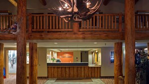 A lobby with a reception desk, wooden pillars, and a chandelier.