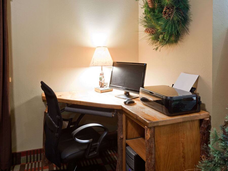 Un bureau en bois avec un ordinateur, une lampe et une imprimante.