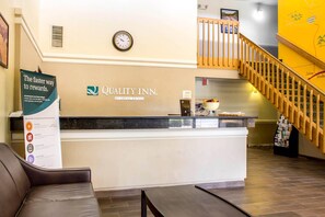 A reception desk with a clock, a sign for the Quality Inn, and a staircase. - Quality Inn Wickenburg (Wickenburg)