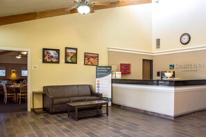 A hotel lobby with a reception desk, a brown leather sofa, a coffee table, and framed artwork on the wall. - Quality Inn Wickenburg (Wickenburg)