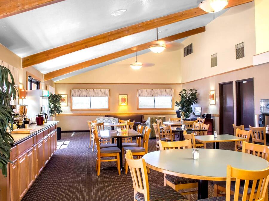 A restaurant with wooden beams, tables, chairs, and potted plants.