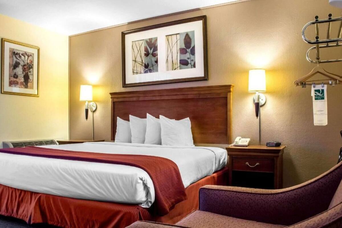 A hotel room with a large bed, two bedside tables, a chair, and artwork on the walls.