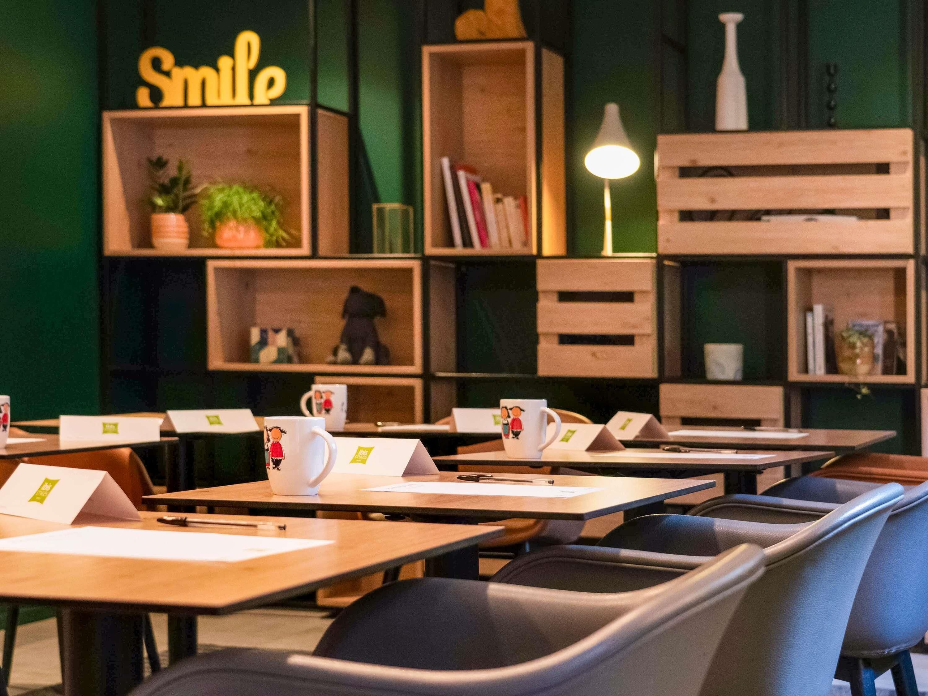 Un café acogedor con mesas y sillas de madera, y estanterías llenas de libros y objetos decorativos.