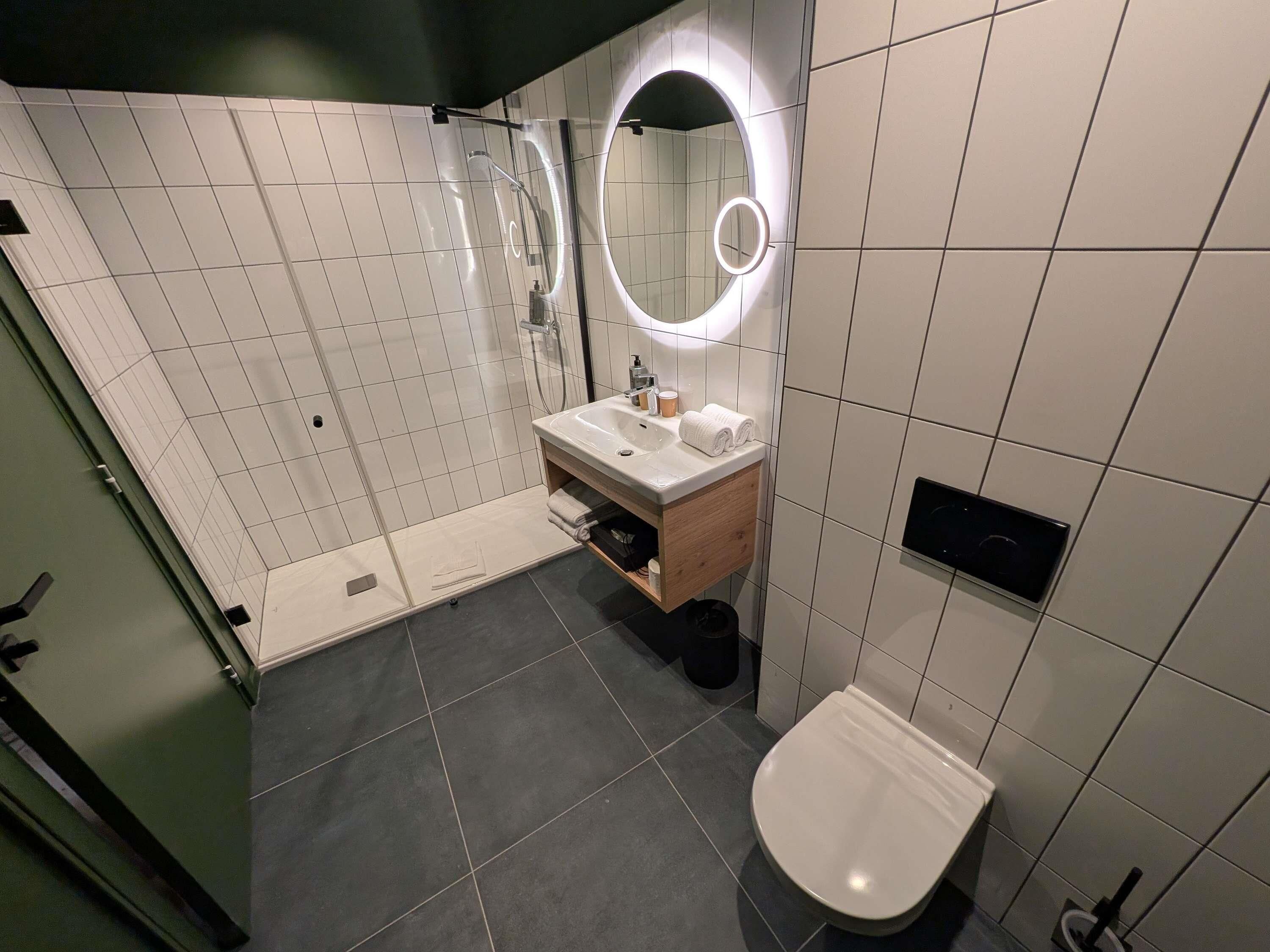 A modern bathroom with a shower, toilet, and sink.
