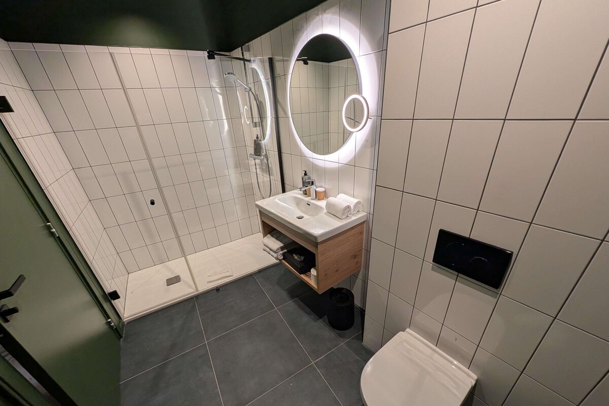 A modern bathroom with a shower, toilet, and sink.
