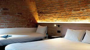 A hotel room with two beds, a brick wall, and a wooden headboard. - ibis Styles Colmar Centre (Colmar)