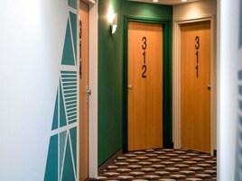 Un pasillo con puertas numeradas 312 y 313, suelo con diseño y pared verde.