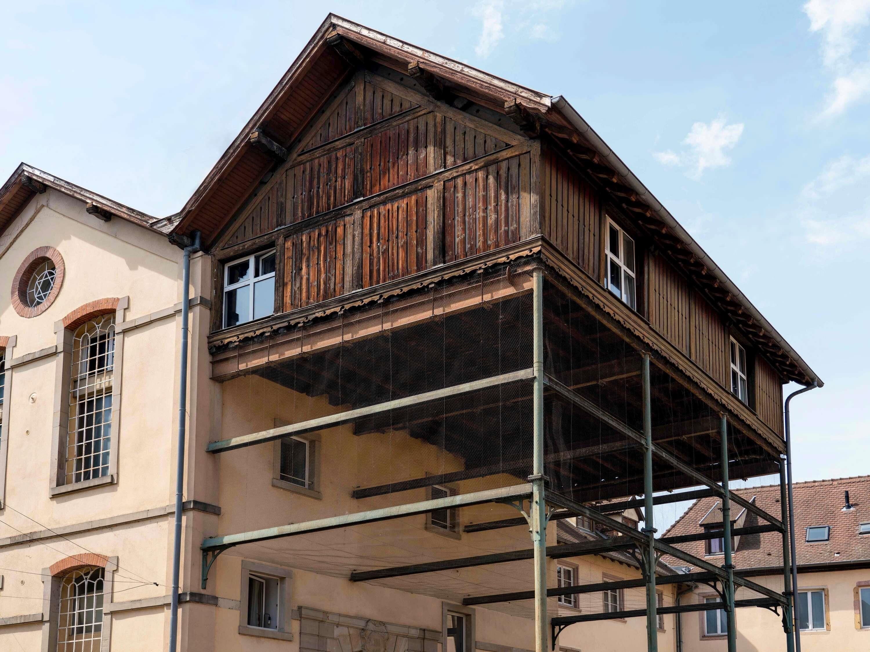 Un edificio con fachada de madera, un balcón y una ventana con diseño en forma de estrella.