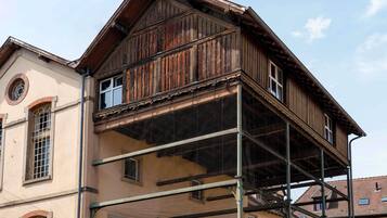 Un edificio con fachada de madera, un balcón y una ventana con diseño en forma de estrella.