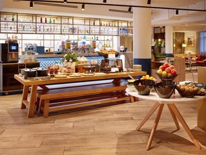 A buffet setup with various food items and a kitchen area in the background. - Radisson Hotel Aix en Provence (Aix-en-Provence)