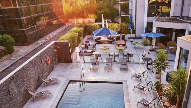 A rooftop pool area with lounge chairs, umbrellas, and a small seating area. - Radisson Hotel Aix en Provence (Aix-en-Provence)