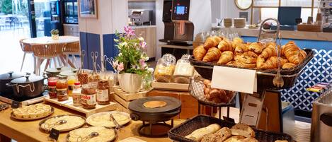 Un buffet proposant une variété de plats, notamment des pâtisseries, du pain et des condiments.