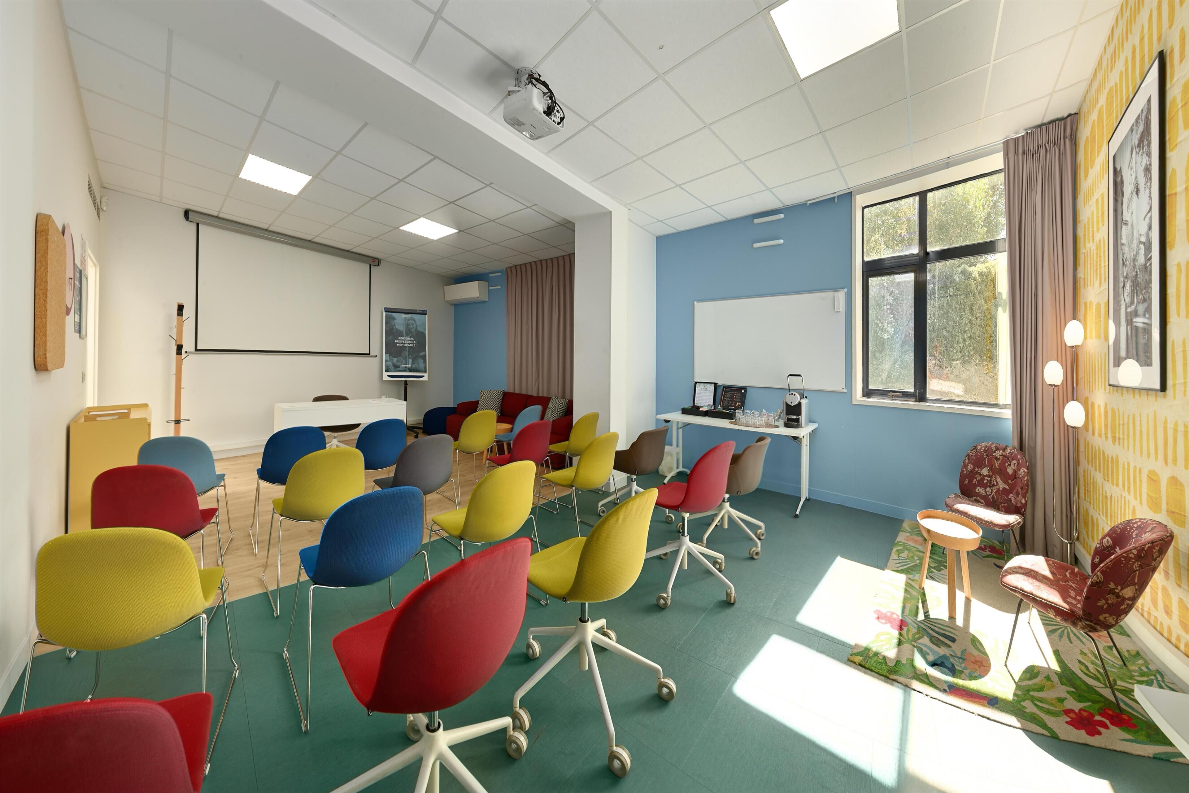 A conference room with colorful chairs, a projector, and a whiteboard.
