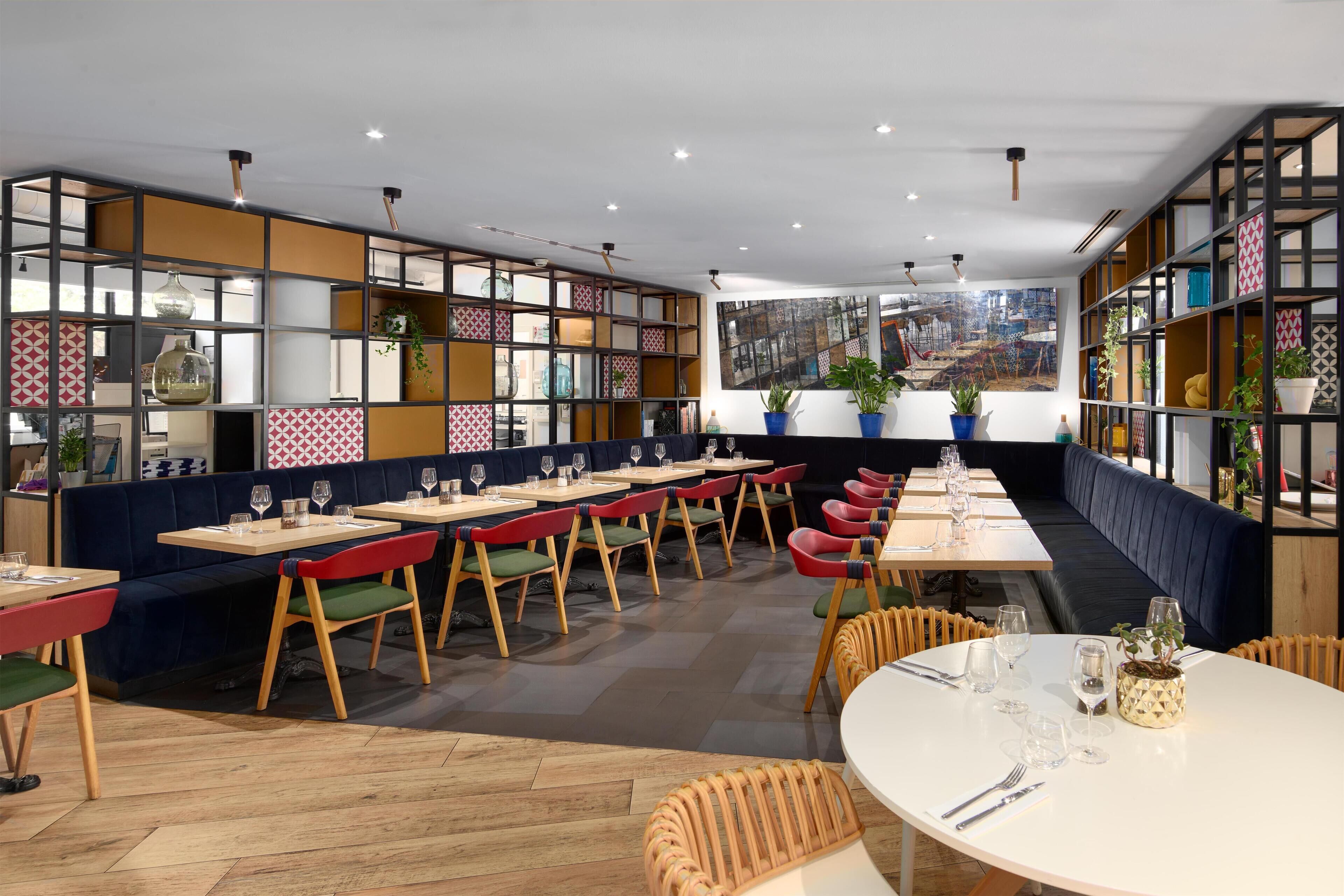 Un ristorante moderno con banquette e tavoli, pavimento in legno e vista sulla città.