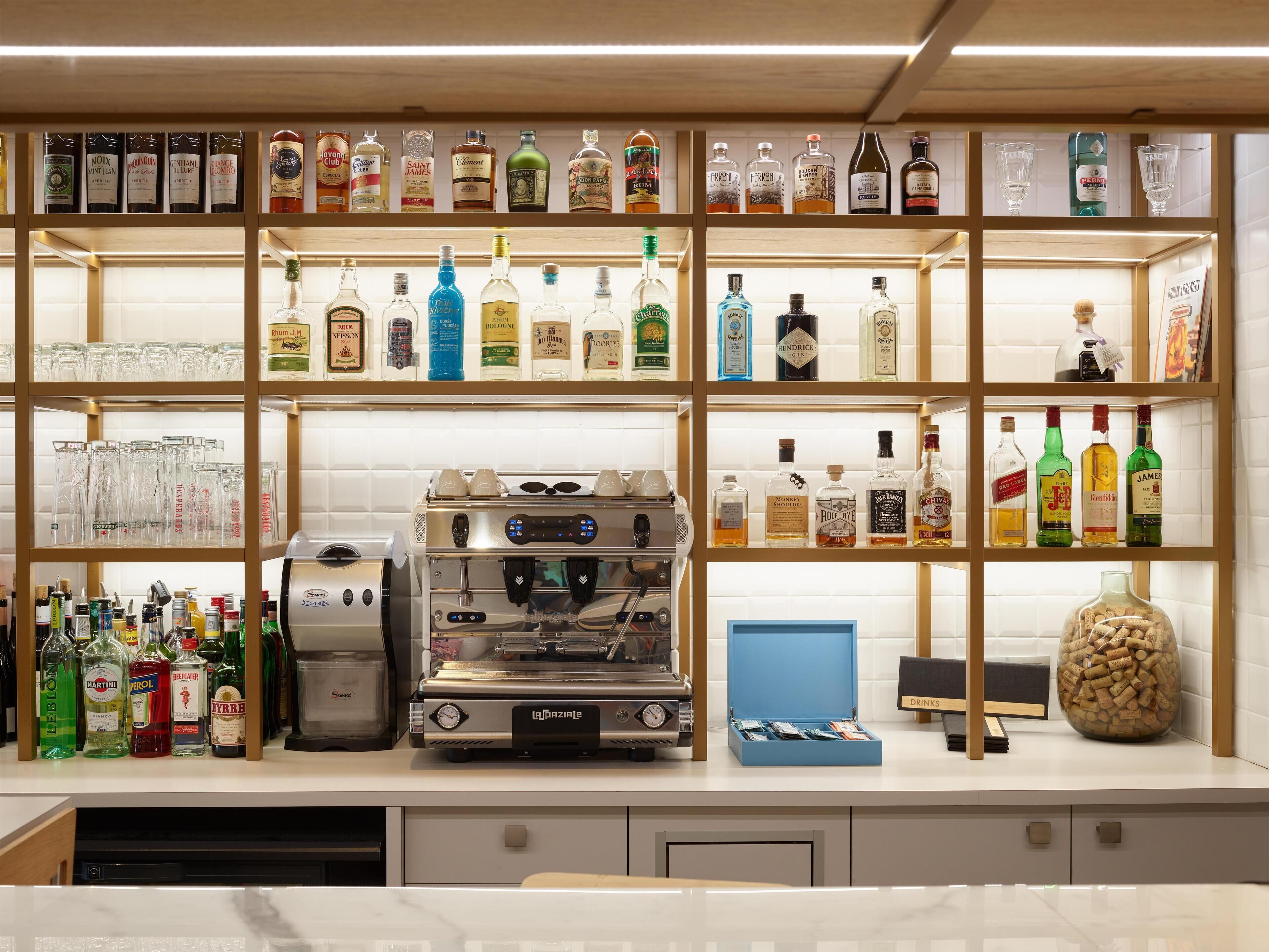 Een bar met flessen drank en een koffieapparaat.