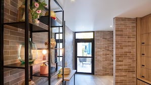 A modern interior with brick walls, a wooden cabinet, and a glass shelf with decorative items. - Radisson Hotel Aix en Provence (Aix-en-Provence)