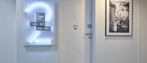 A hotel entrance with a modern illuminated sign indicating room numbers 201-219 and 2nd floor.